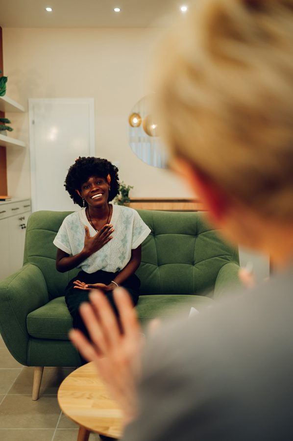 A happy woman is sitting with a physiotherapist in the office and smiling at her during her session. Mental health awareness day, self-care. A woman is smiling at the therapist in session.